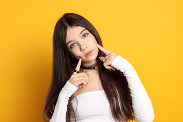 Teenage girl wearing stylish clothes and accessories on orange background. Makeup in anime style