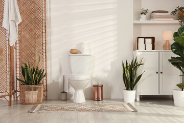 Ceramic toilet bowl, houseplants and necessities in restroom