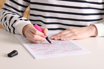 Woman highlighting important information at white desk indoors, closeup