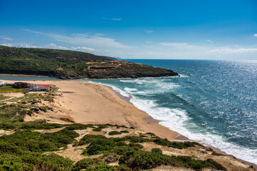 view of Foz do Lizandro beach in Ericeira, Portugal, with golden sand, waves, and coastal landscape on a sunny day.