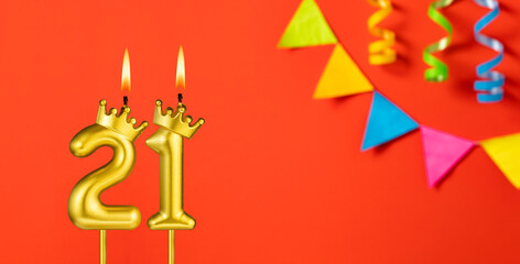 Number 21 candle - Birthday celebration on an orange background with pennants