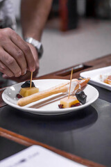 Chef preparing delicious appetizers with grissini, cheese, and prunes