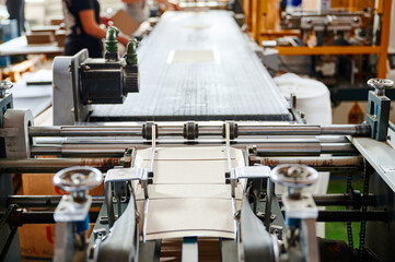 Machine efficiently folds flaps of cardboard boxes in a busy packaging facility during the daytime