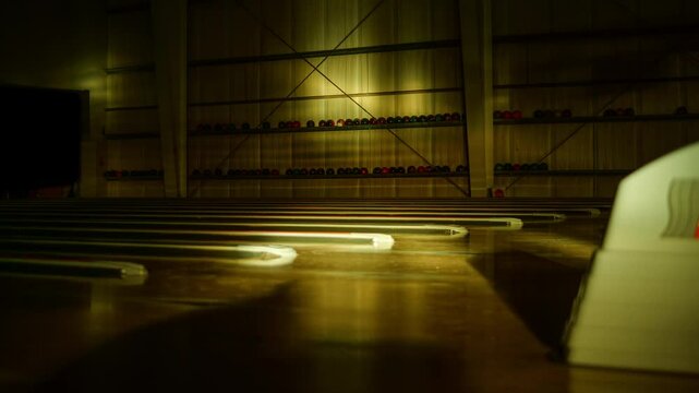Long shadows drift across quiet lanes in empty retro-style bowling environment