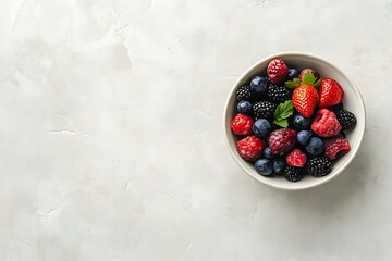 Top view of fresh ripe mixed berries in bowl on light grey table