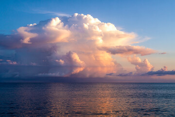Golden Hour Over Tranquil Ocean Waters With Towering Cumulus Clouds