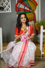 Beautiful Indian woman in saree, adorned with gold jewellery, holding lotus bouquet