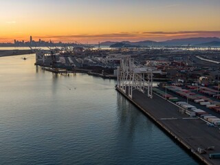 Oakland, USA: A tugboat navigates the Oakland Estuary at dusk, with the Port of Oakland's cranes...