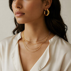 Woman wearing chunky gold hoop earrings and a layered gold chain necklace, set against a soft, neutral background with warm lighting that highlights the jewelry shine.