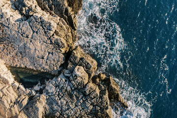 Blue sea rolls onto the rocky shore. Top view