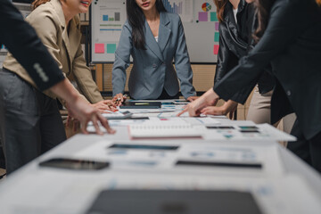 Businesswomen in meeting room reviewing financial reports, analyzing charts, and discussing strategies for corporate success, demonstrating teamwork and collaboration in modern office environment
