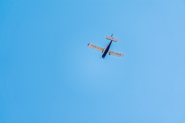 Small ultralight airplane with overhead wing and single propeller flying in sunset sky.