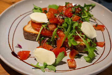 Salad on toast with salad dressing served on plate, on the table