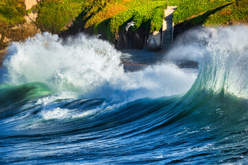 Powerful ocean waves with turquoise and blue hues crash and foam, creating a dynamic and energetic...