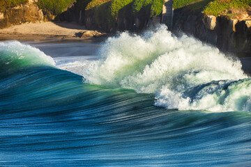 Powerful ocean waves with turquoise and blue hues crash and foam, creating a dynamic and energetic...