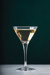 Italian white bianco vermouth in glass on dark green background