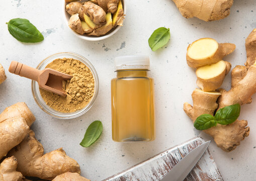 Bottle of immune ginger energy shot drink with ginger root and grounded powder on light background.Macro.