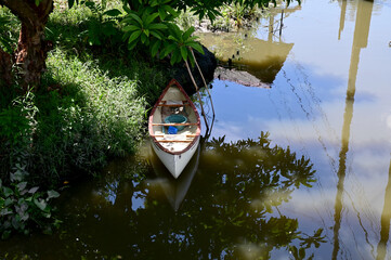 Closeup of A white canoe is on the bank of a canal in the garden with natural background at Thailand.