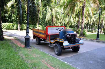 BANGKOK, THAILAND - April 15, 2025 : Closeup of The Old Car E-Taen (Thai farmer's car) with flowers parked in the garage at Thailand.