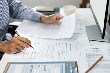 asian businessman reviewing contract document at office. legal expert, professional lawyer working with computer reading and checking financial documents and business contract