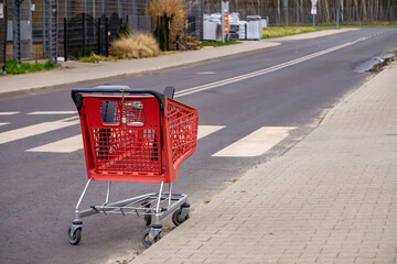 A red shopping cart left at a pedestrian crossing on an empty street © Adam