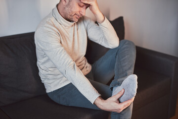 Fototapeta premium Man with ankle and foot pain at home.