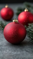Red christmas balls with shiny textures and evergreen needles on stone background, holiday atmosphere