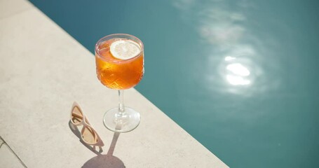 Swimming pool, glass and cocktail with sunglasses for holiday, summer vacation or relax outdoor. Water, alcohol and drink at hotel resort for tourism, travel and luxury with fresh lemon in top view
