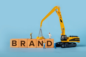 The word BRAND is written on a wooden box, miniature people and excavator trucks make up the box.