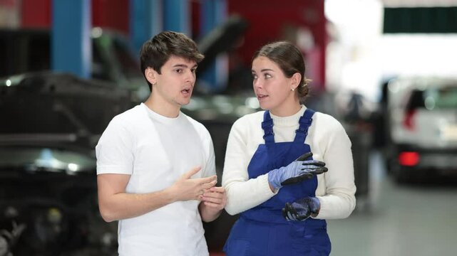 European guy consults with a car service worker about the repair and diagnostics of the car. Female mechanic gives recommendations for changing the oil, filter and checking the engine. High quality 4k