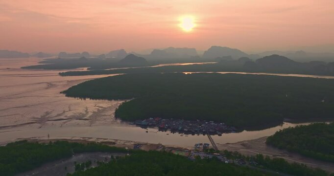 Aerial view of A small bridge connects to a fishing village that lives on a small island surrounded by mangrove forests. In front is a canal that leads to the sea, rich in various marine life.