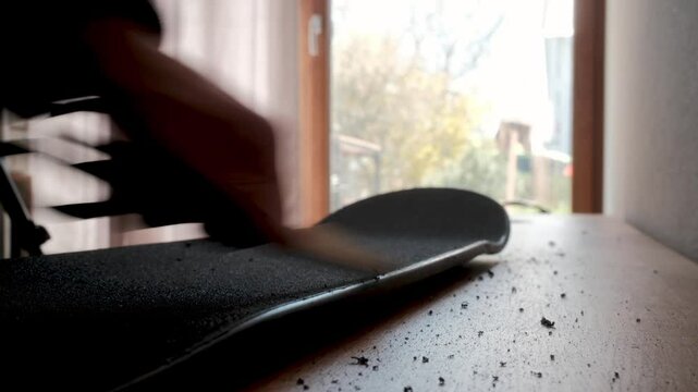 Side view of finishing a skateboard after applying a griptape with a scissors. Typical process for a skater.