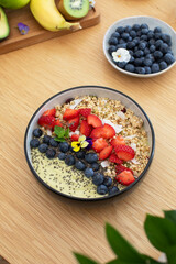 Healthy breakfast avocado smoothie bowl with fresh fruits and chia seeds on wooden table