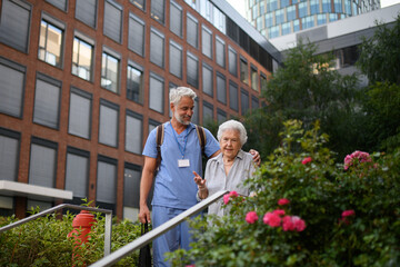 Caring healthcare worker helping elderly woman walk the stairs.