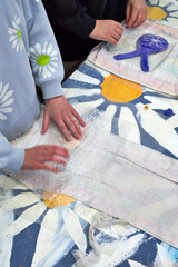 A view from above of the table with a daisy pattern, where a master class on felting toys from wool is taking place