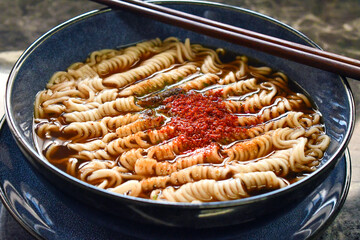 Instant noodles soup with seasoning and chilli flakes with chopsticks in a bowl. Asian dish. Spicy...