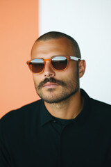 Obraz premium Portrait of stylish man wearing sunglasses and black shirt on colorful background