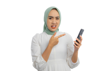 Beautiful young Asian woman in green hijab and white blouse pointing finger at mobile phone with confused expression isolated on transparent background