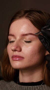 Makeup artist workplace does her eyebrows in front of the mirror