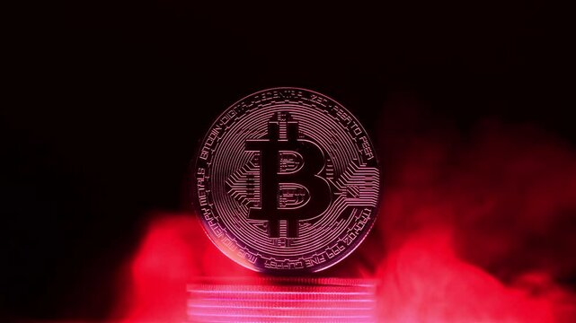 Glowing bitcoin is standing on a stack of coins surrounded by red smoke on a dark background with copy space, representing the mysterious nature of cryptocurrency