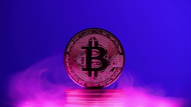 Bitcoin cryptocurrency coin hovering over stack of coins on blue background with pink smoke, representing investment, finance, and digital currency