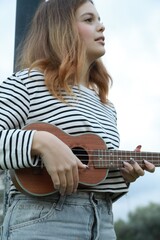 Fototapeta premium Artist Girl Plays Ukulele Musical Instrument Outside In Park
