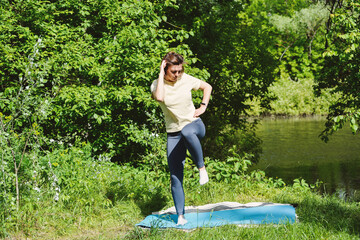 Woman practicing yoga balance pose by lakeside.
