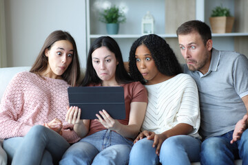 Obraz premium Perplexed group of friends checking tablet at home