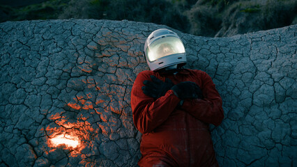 Astronaut With Helmet Lying On A Rock At Night On A Lifeless Planet