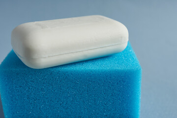 Close up of a sponge and soap on blue background. Shallow depth of field.