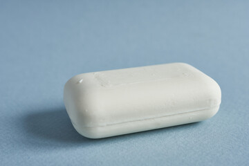 Bar of white soap on a blue background. Close-up.