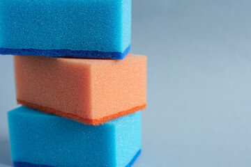 Colorful sponges for washing dishes on a blue background.