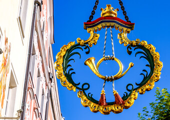 Beautifully detailed sign hanging in the blue sky of a historic city showcasing craftsmanship in outdoor decoration and design