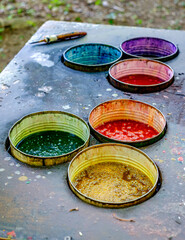 Vivid colors in circular containers arranged on a weathered table outdoors
